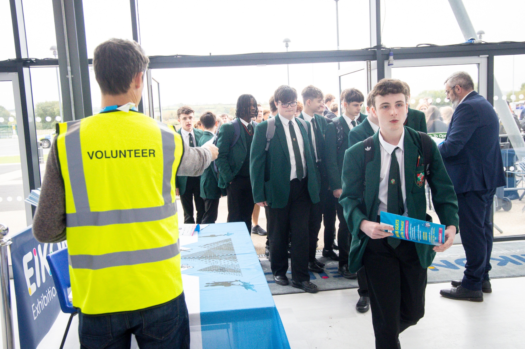 A British Army officer in uniform speaking with two secondary-school pupils in green blazers at School Summit Northern Ireland, 2025.