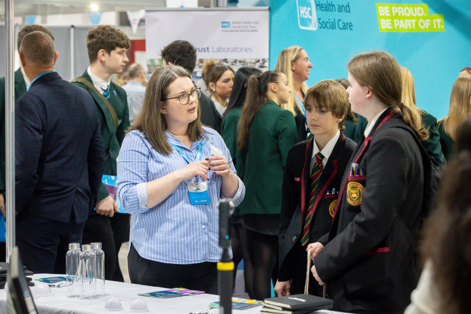 A teacher and pupils in conversation with an exhibitor at a branded stand at School Summit Northern Ireland, 2025.