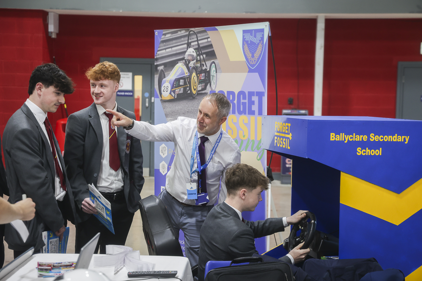 Ballyclare Secondary pupils gathered around a hands-on racing simulator stand at School Summit Northern Ireland, 2024.