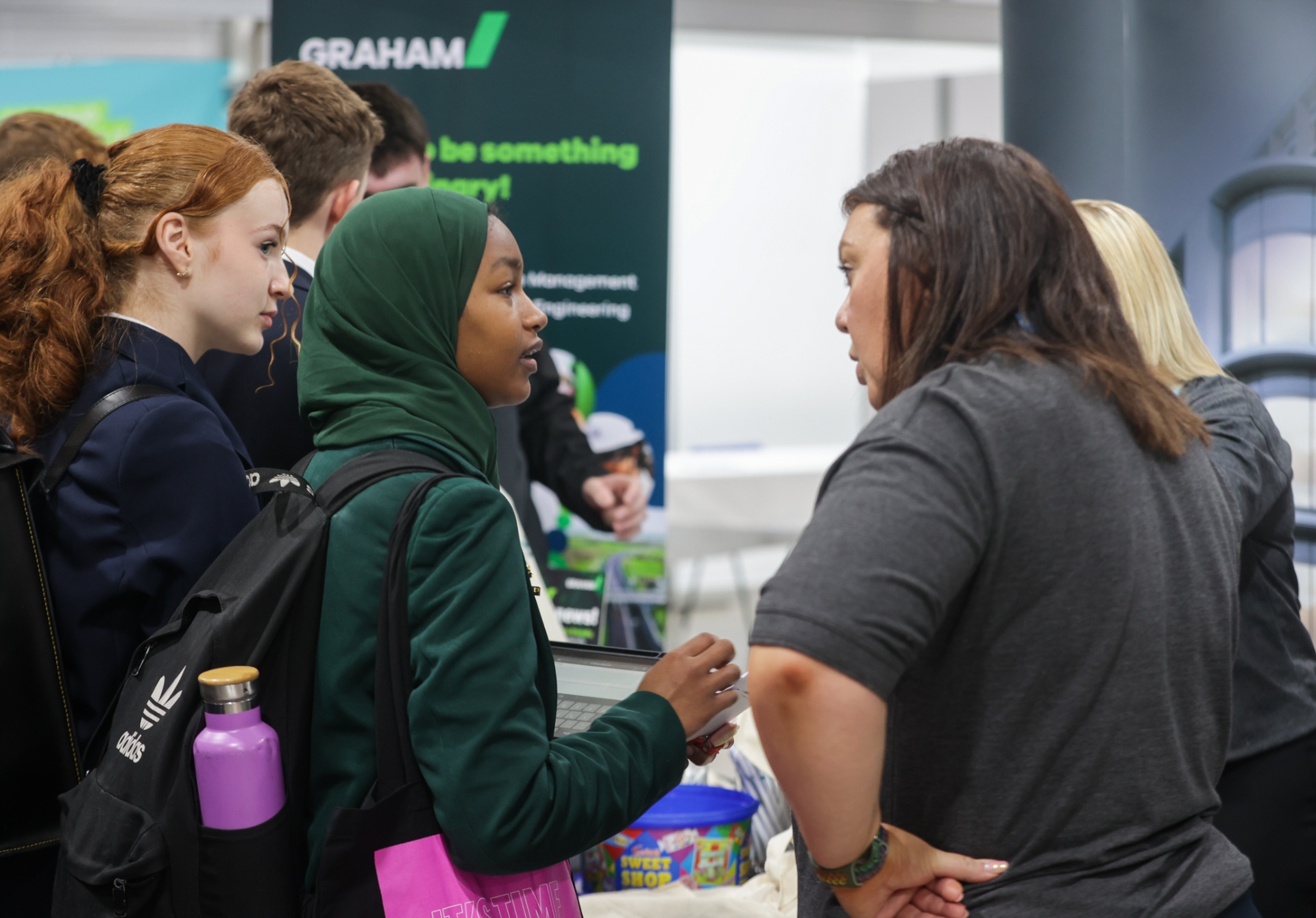 A secondary-school pupil wearing a hijab in conversation with a GRAHAM ‘Be Something Extraordinary’ exhibitor at School Summit Northern Ireland, 2023.