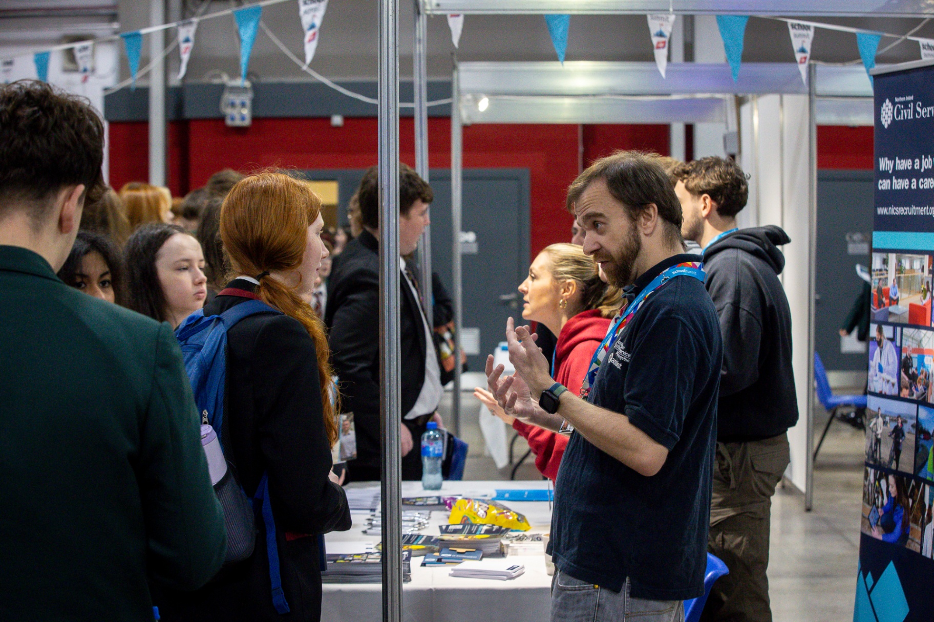 A Northern Ireland Civil Service representative in an animated conversation with visiting pupils at School Summit Northern Ireland.