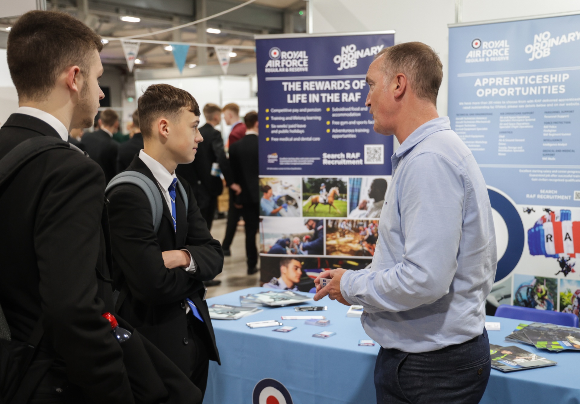 A secondary-school pupil in blazer speaking with a Royal Air Force recruiter at the RAF Apprenticeship Opportunities exhibitor stand, 2023.