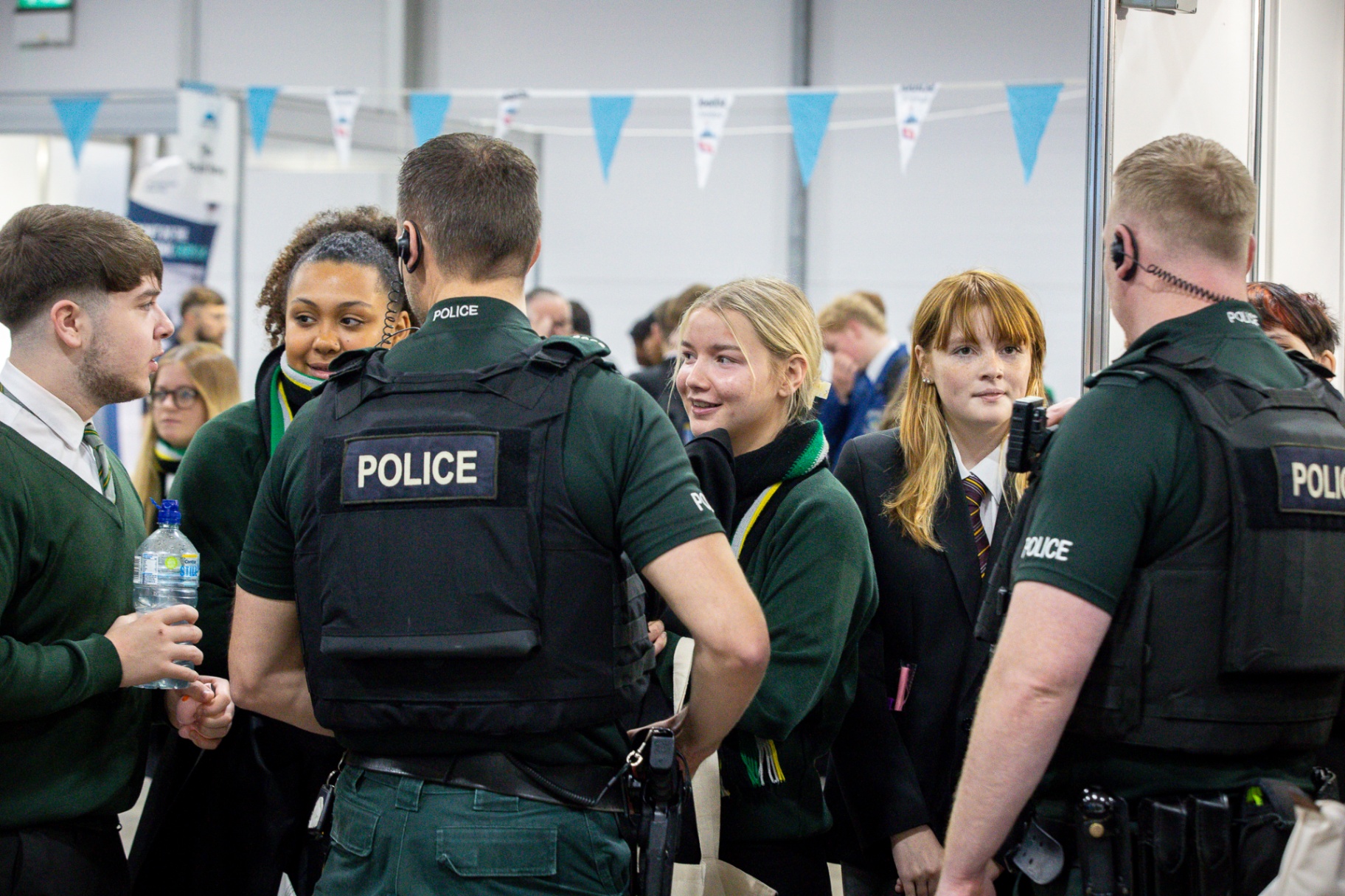 PSNI police officers in high-visibility vests in animated conversation with a group of pupils at School Summit Northern Ireland.